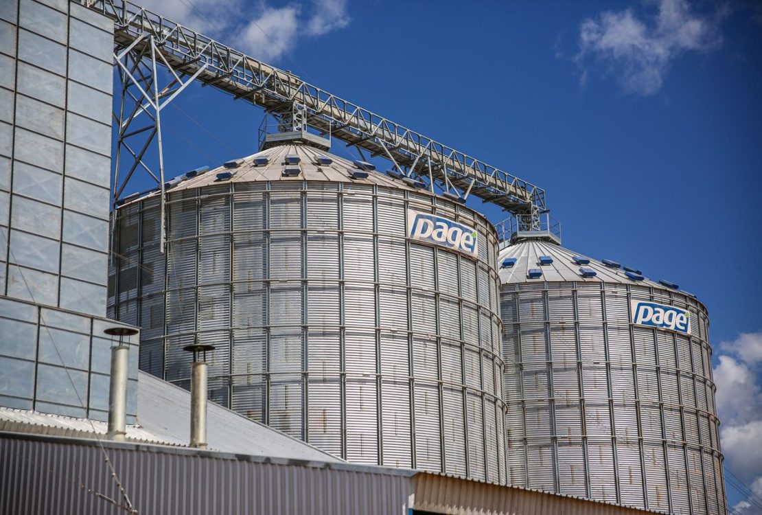 Silos industriais de armazenamento de grãos em uma área agrícola sob céu azul.