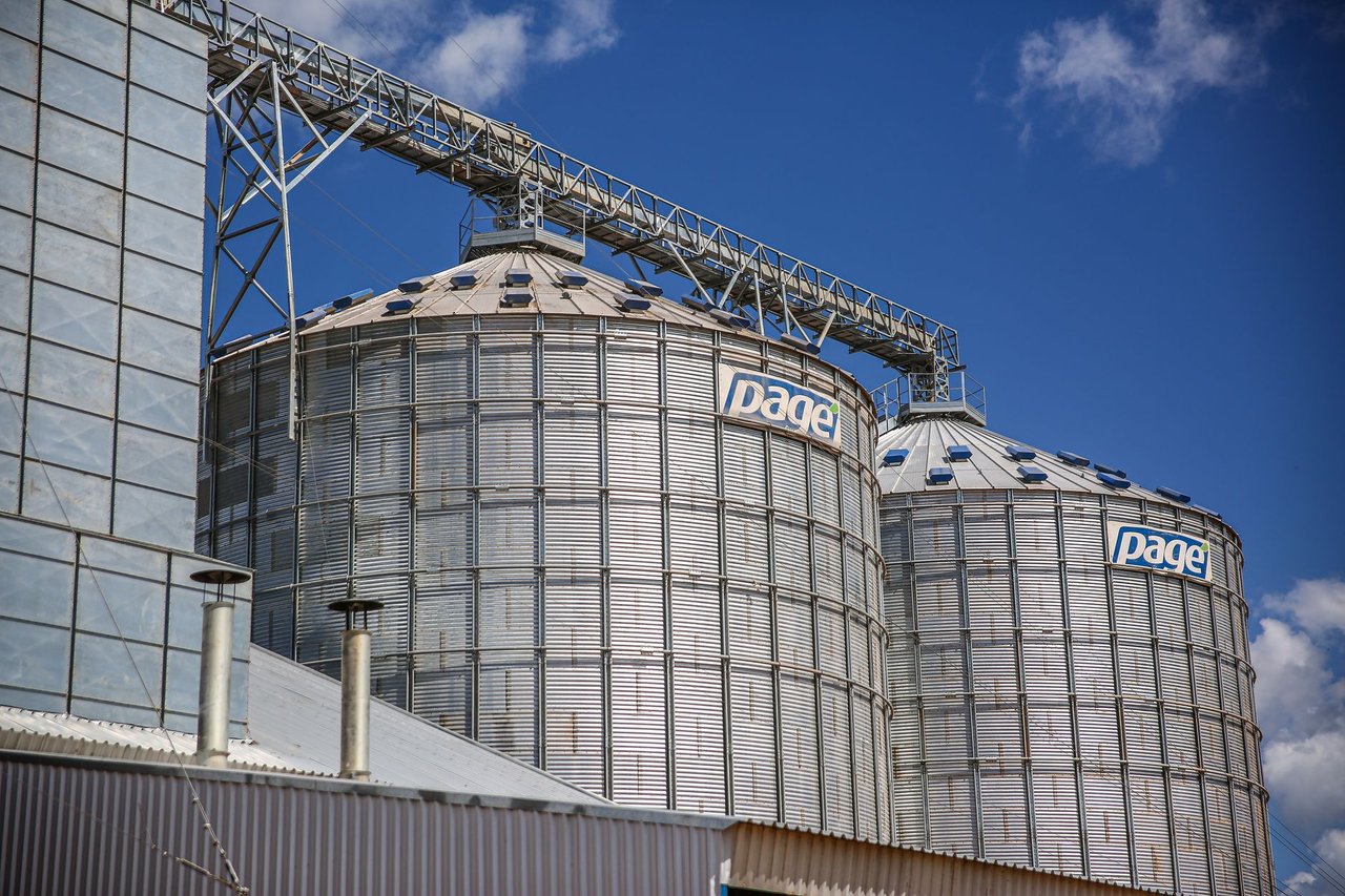 Silos industriais de armazenamento de grãos em uma área agrícola sob céu azul.