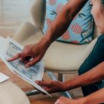Duas pessoas analisam documentos financeiros em um ambiente de trabalho.