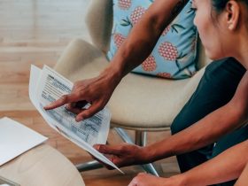 Duas pessoas analisam documentos financeiros em um ambiente de trabalho.