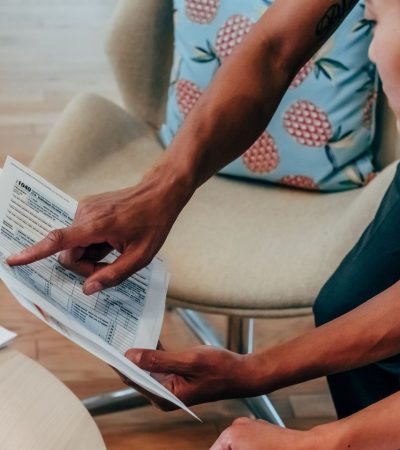 Duas pessoas analisam documentos financeiros em um ambiente de trabalho.