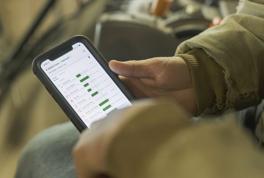 Pessoa vestida para o inverno consulta dados agrícolas em um smartphone.