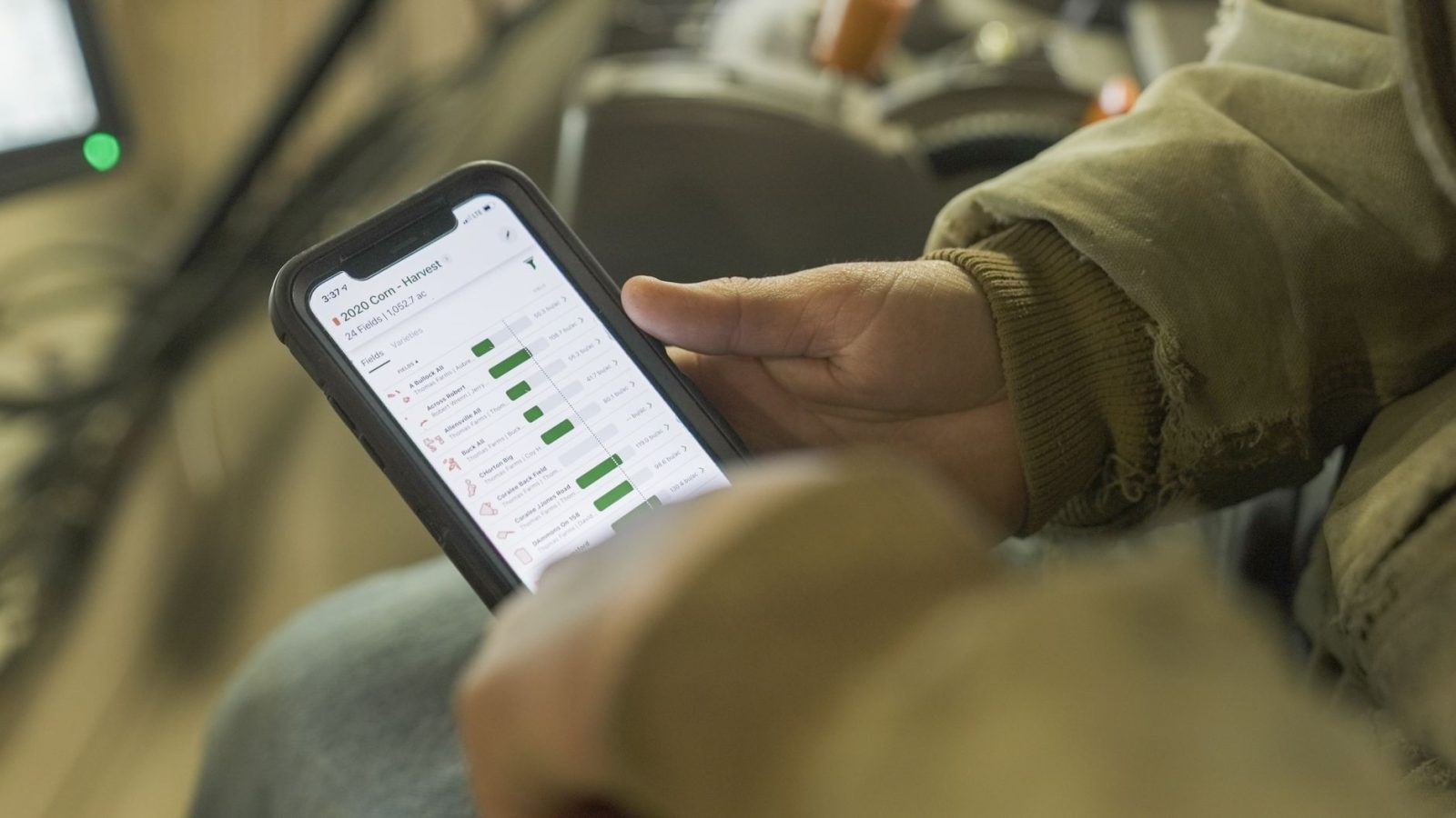 Pessoa vestida para o inverno consulta dados agrícolas em um smartphone.