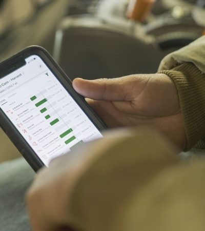 Pessoa vestida para o inverno consulta dados agrícolas em um smartphone.